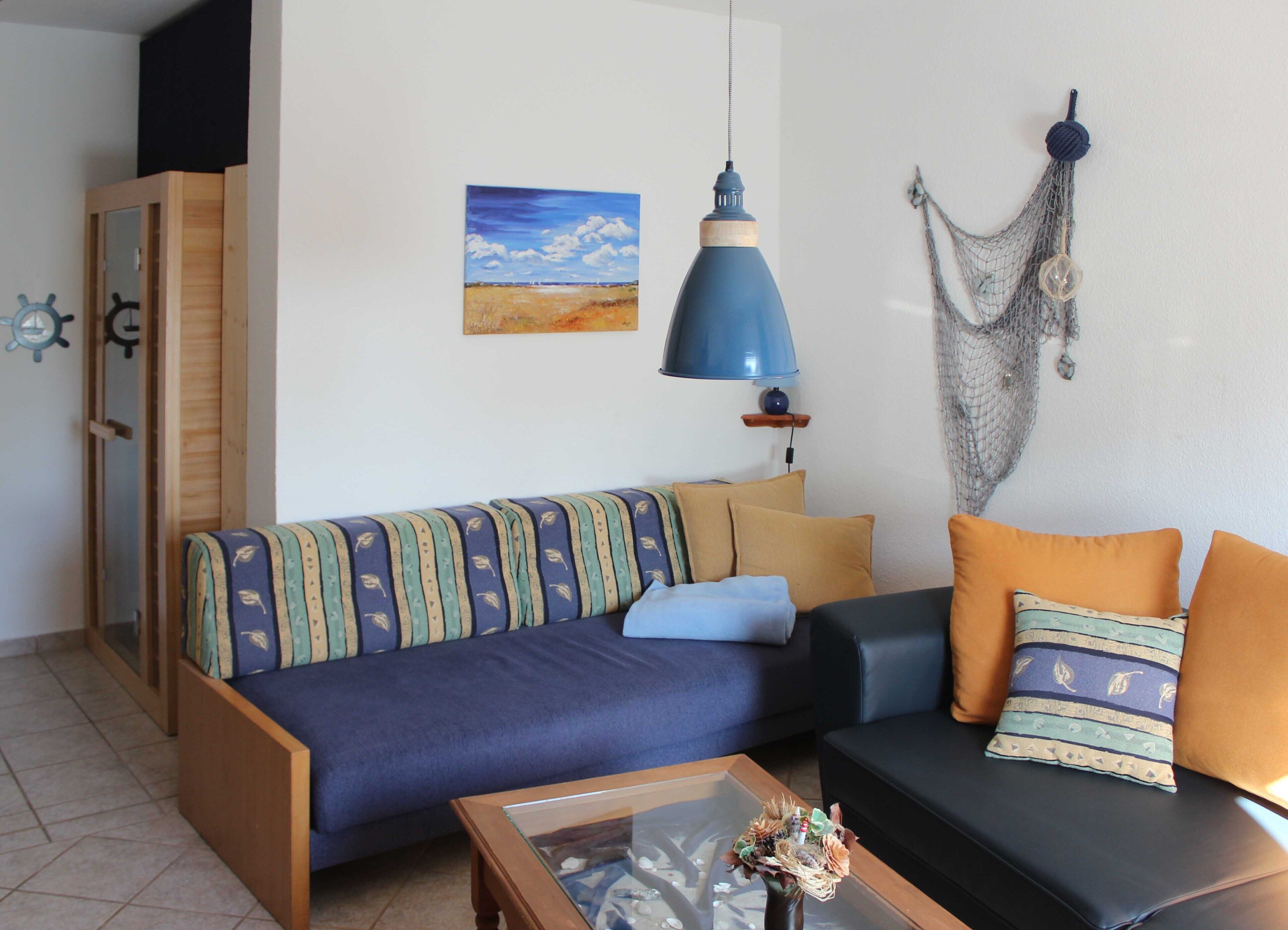 Ein Wohnzimmer mit einer Couch, einem Couchtisch, einem Gemälde und einer Hängeleuchte.