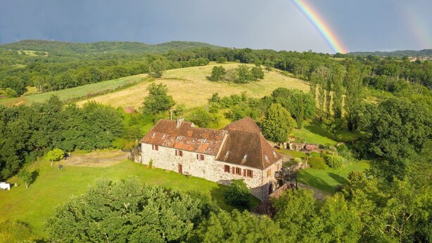 A stone building with a sloped roof surrounded by lush greenery and hills. - 6 bedroom manor house in large property with pool and garden, games room (Curemonte)