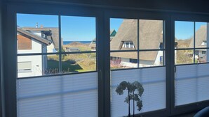 A room with a large window overlooking a coastal village with traditional houses and a clear sky. - 5 star hotel according to DTV - pure luxury, only 200m from the beach - WLAN free of charge (Dranske)