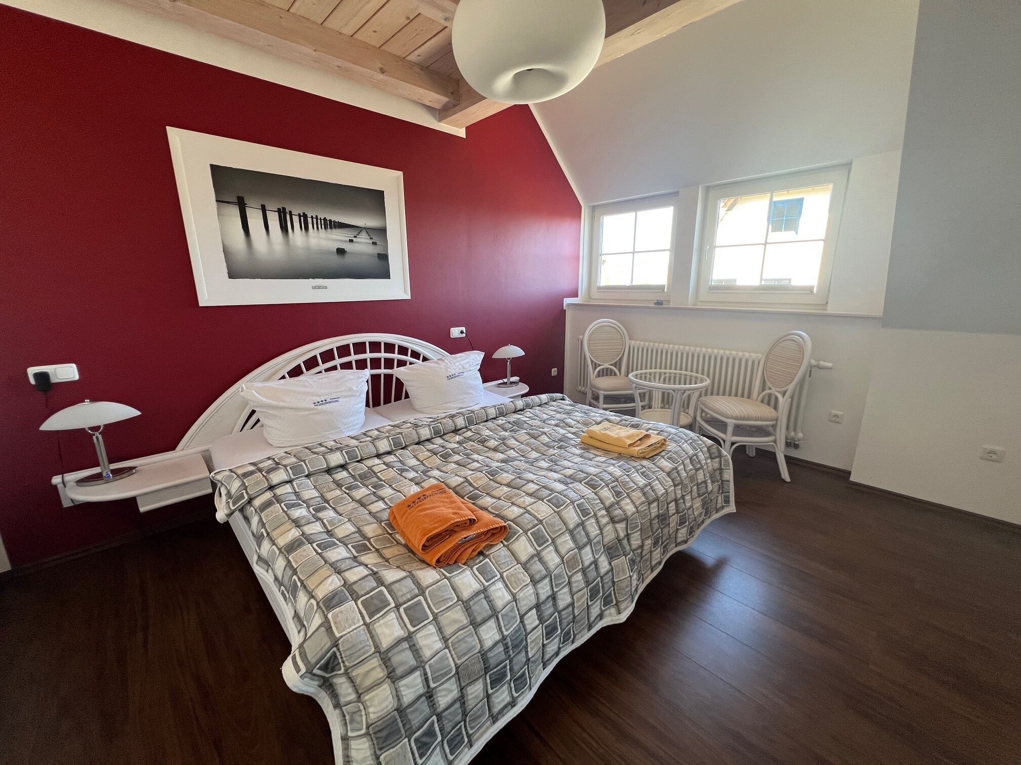 Un dormitorio con cama, silla, mesa y ventana.