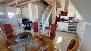 A spacious living area with a dining table and chairs, a staircase, and a kitchen area with red cabinets. - 5 star hotel according to DTV - pure luxury, only 200m from the beach - WLAN free of charge (Dranske)