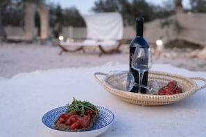 Una mesa con una botella de vino, una copa y dos platos de comida.