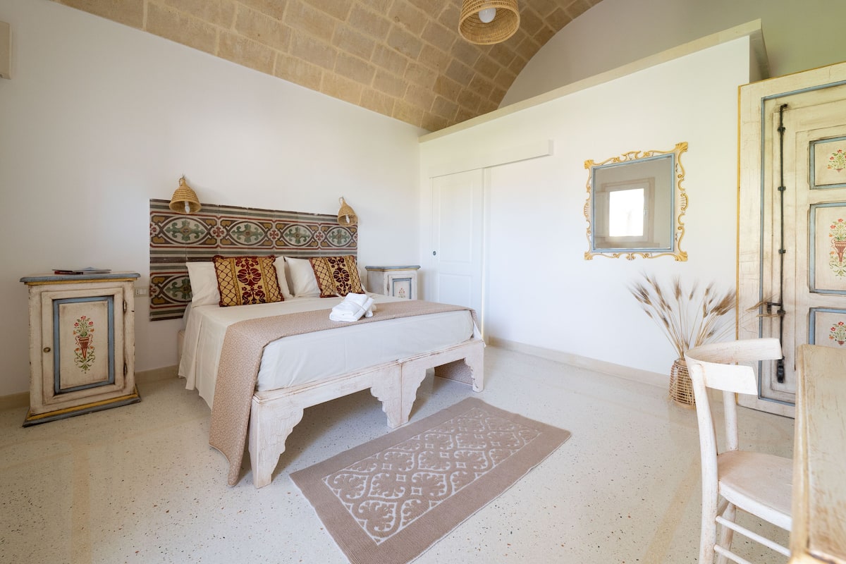 A bedroom with a bed, a bedside table, a wardrobe, and a mirror.