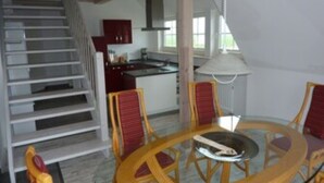 Un escalier menant à une cuisine équipée d’une table et de chaises.