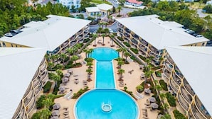 A resort with a central pool, multiple balconies, and surrounding palm trees. - Adagio B-203 Beach Front 4/3 - Beautiful Unit with Beautiful Views! (Santa Rosa Beach)