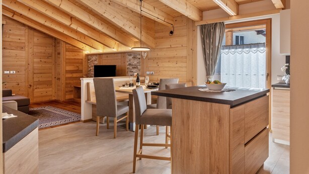 A modern log cabin interior with a dining area, kitchen, and a cozy seating area.