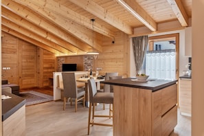 A modern log cabin interior with a dining area, kitchen, and a cozy seating area.