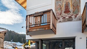 A hotel with a balcony, a mural, and a view of a snowy landscape.