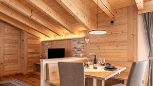 A wooden interior with a dining area, a flat-screen TV, and a stone accent wall.