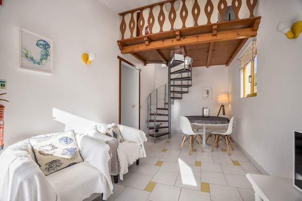 A modern interior with a spiral staircase, a dining area, and a sofa with patterned cushions.