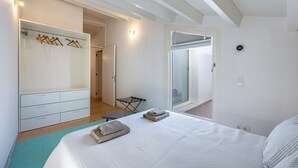 Une chambre à coucher comprenant un lit, une armoire, un miroir et une porte donnant sur un balcon.