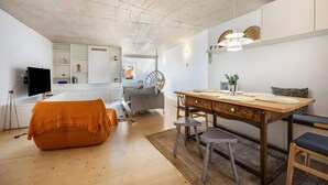 Un espace de vie moderne avec un plafond en bois, un coin repas avec une table en bois, un canapé et un téléviseur.