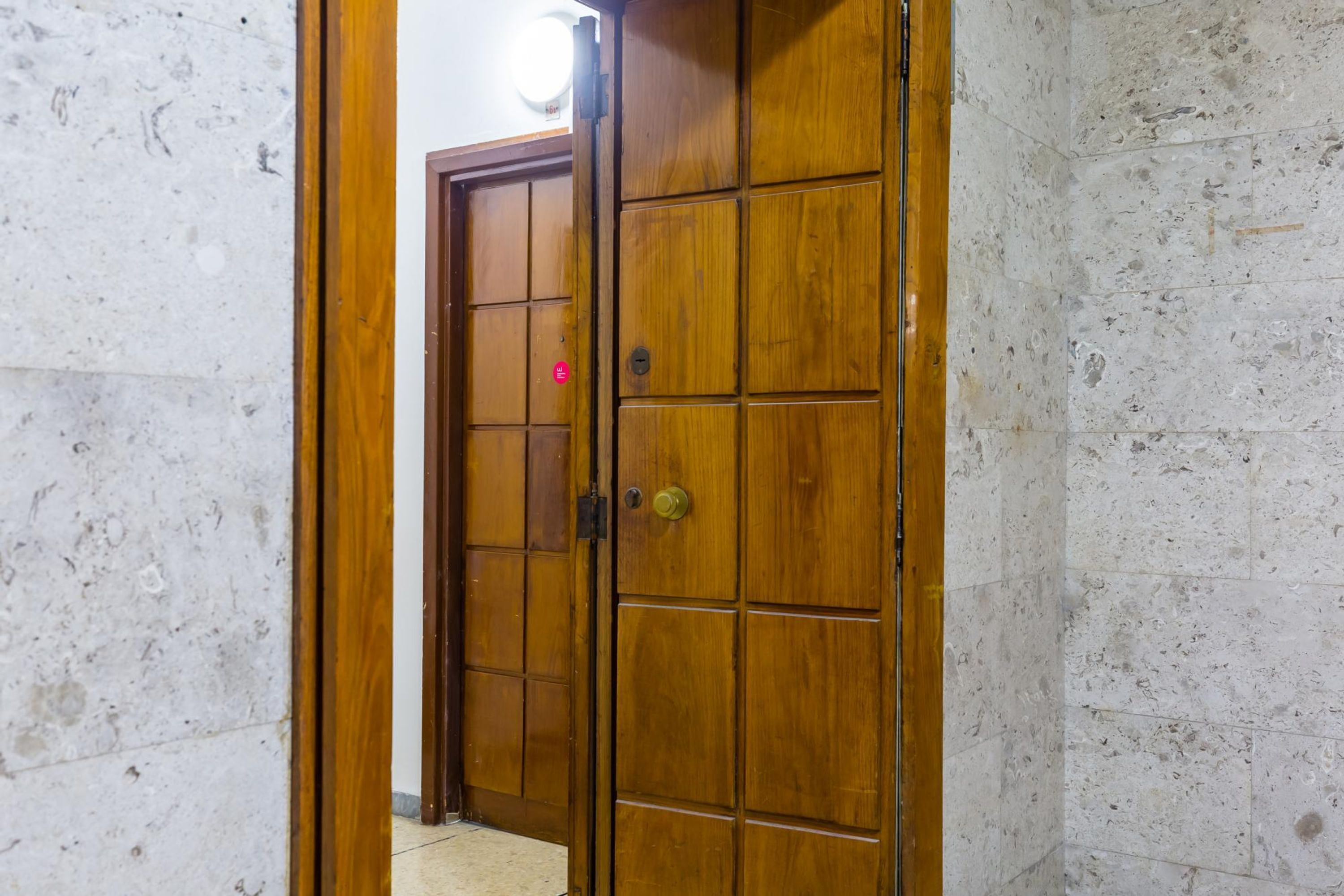 A wooden door with a grid pattern, leading to a hallway with a tiled floor.
