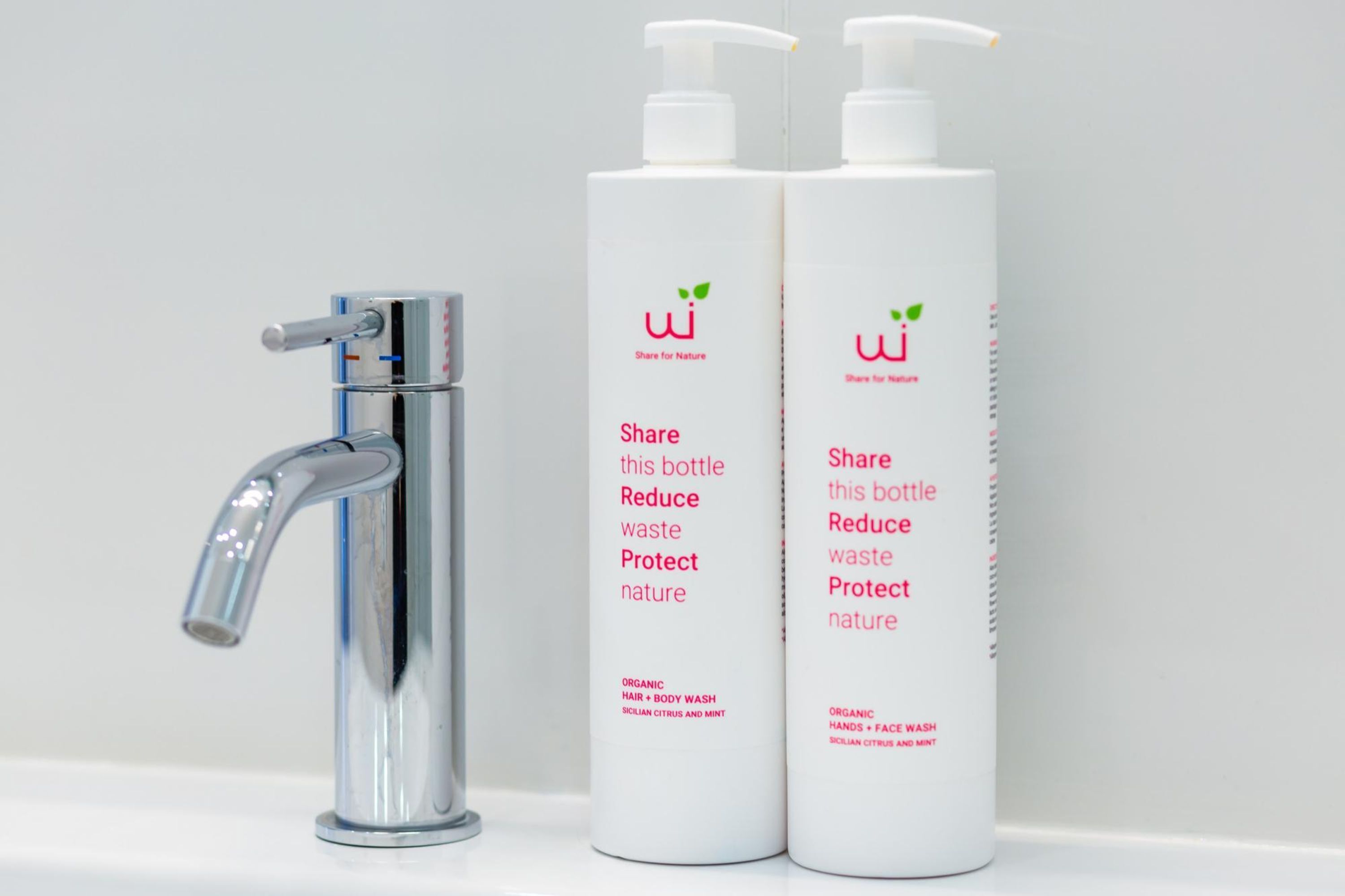 A chrome faucet and two white bottles with pump dispensers labeled "Share for Nature."
