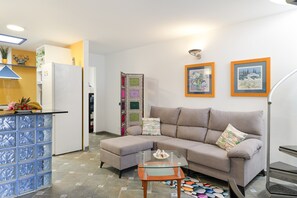 A modern living room with a sofa, ottoman, and glass coffee table.
