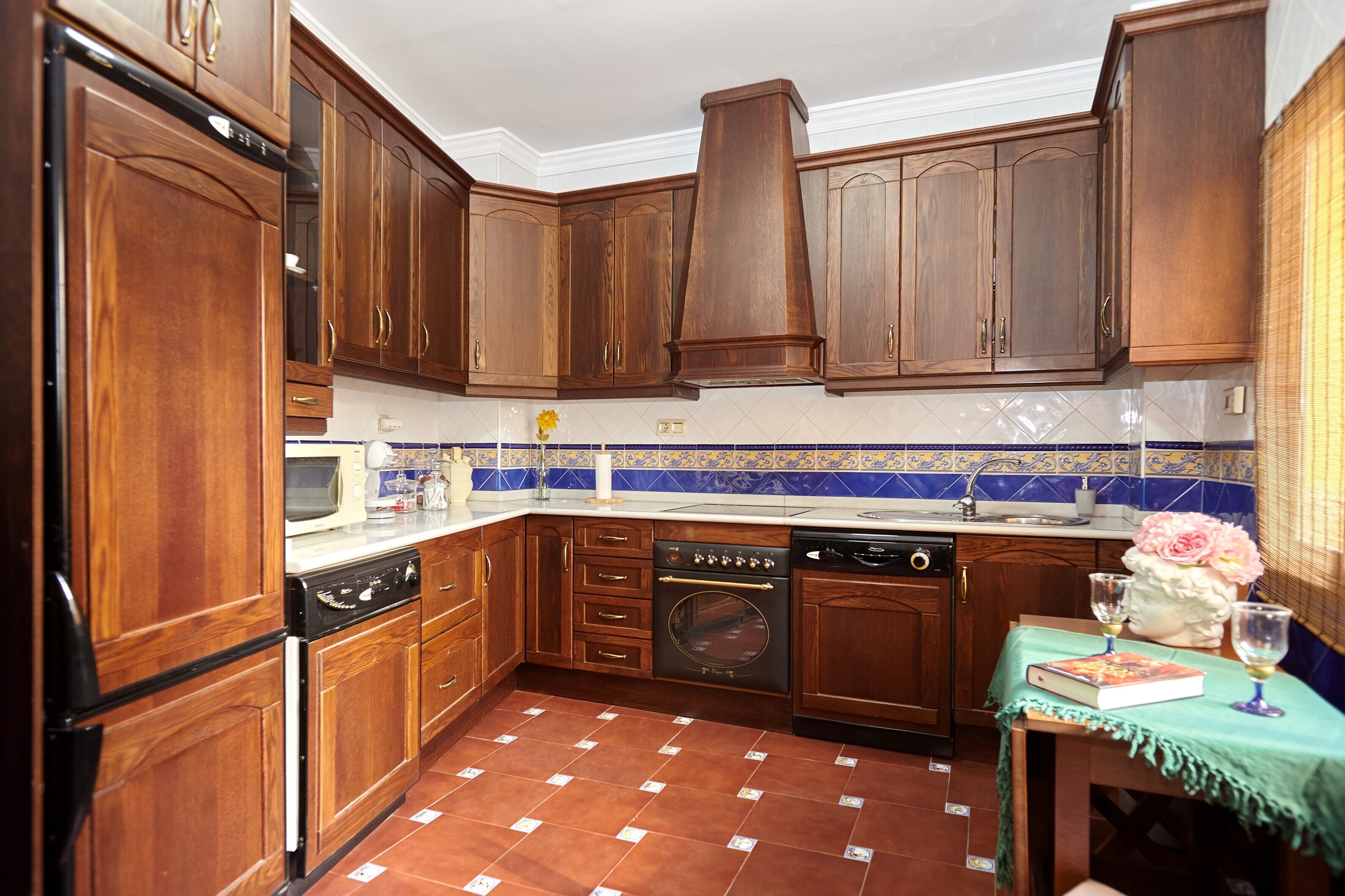 Cuina amb armaris de fusta, rentaplats, forn i salabost a la paret.