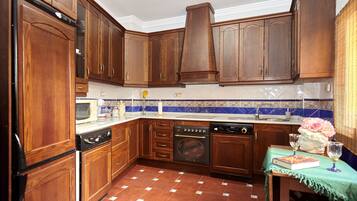 Cuina amb armaris de fusta, rentaplats, forn i salabost a la paret.