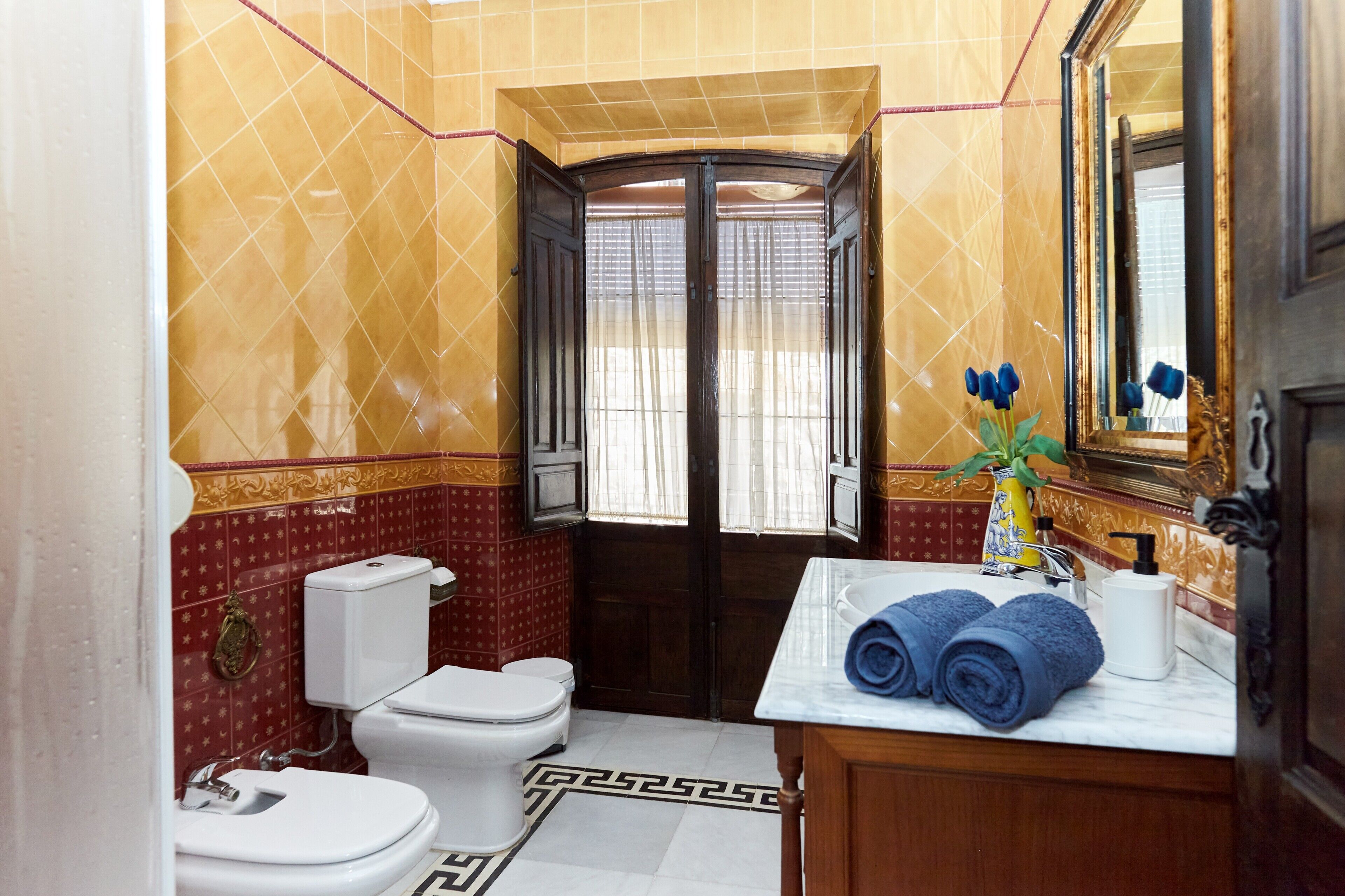 A bathroom with a toilet, sink, and mirror.