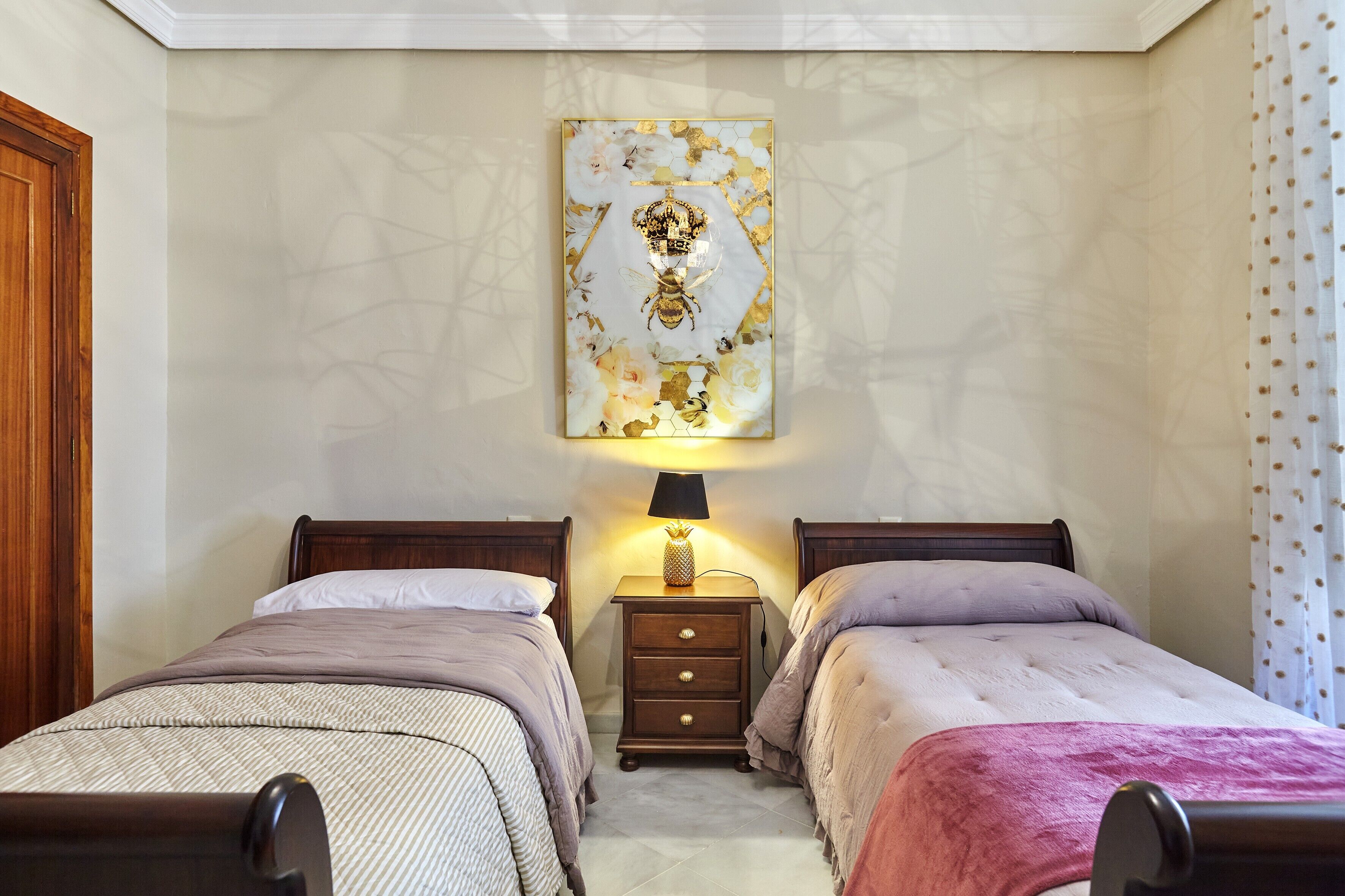 Ein Schlafzimmer mit zwei Einzelbetten, einem Nachttisch mit Lampe und einem Wanddekor.