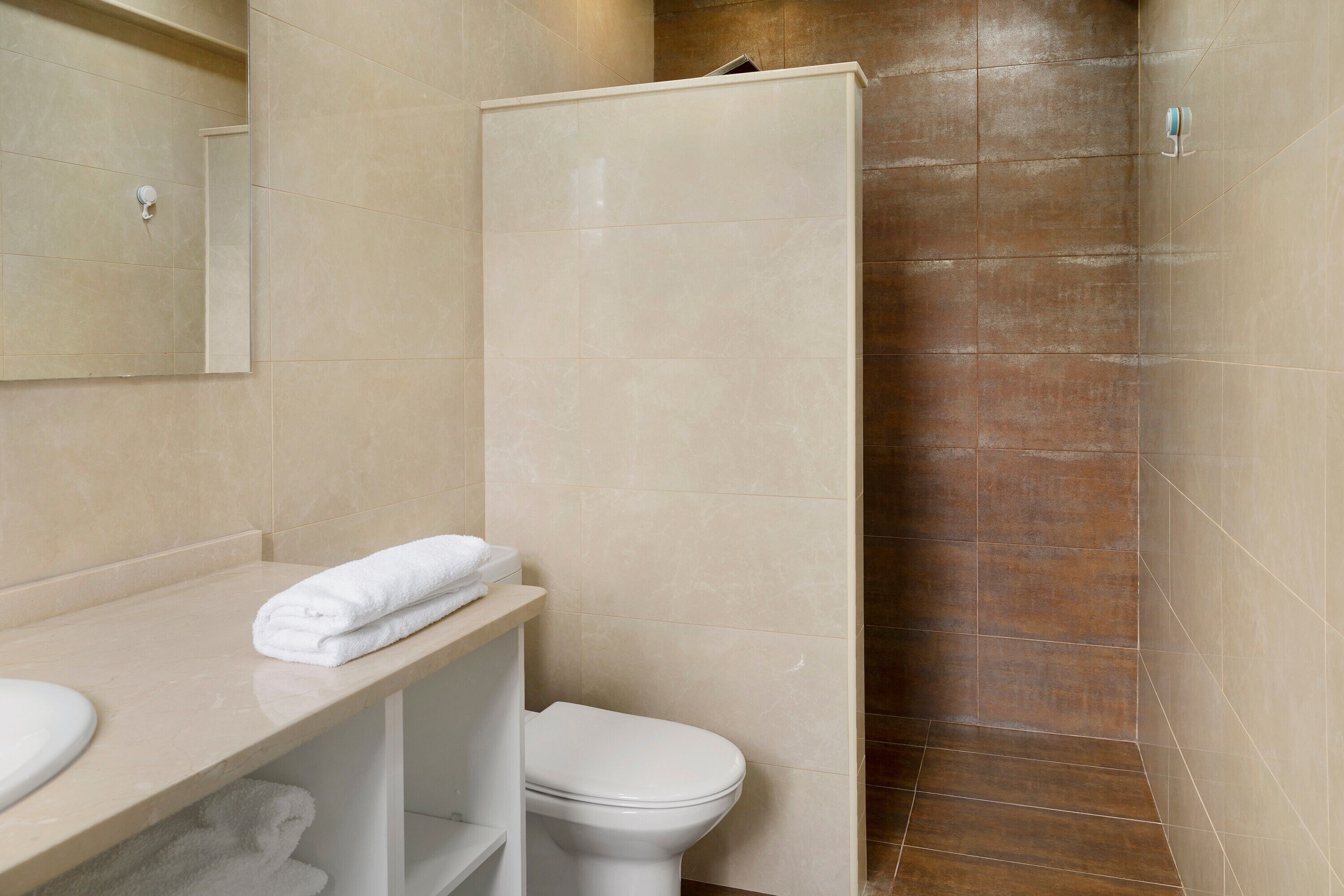 Ein Badezimmer mit Toilette, Waschbecken, Spiegel und Duschkabine.