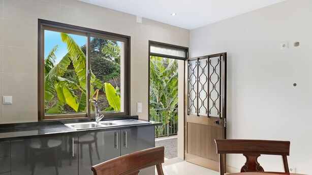 A modern kitchen with a large window, a dining table, and a view of greenery outside. - Holiday Home "Casa T2" with Sea View, Private Terrace & Wi-Fi (Gaula)