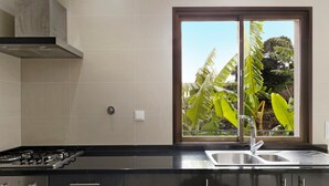 A kitchen with a gas stove, stainless steel sink, and a window with a view of greenery. - Holiday Home "Casa T2" with Sea View, Private Terrace & Wi-Fi (Gaula)