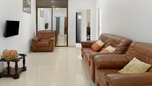 A living room with a brown leather sofa, a brown leather armchair, a wooden coffee table with decorative items, a flat-screen TV mounted on the wall, and a large mirror above the sofa. - Holiday Home "Casa T2" with Sea View, Private Terrace & Wi-Fi (Gaula)