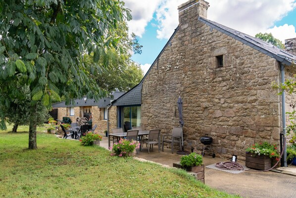 A stone building with a patio area, outdoor seating, and potted plants.