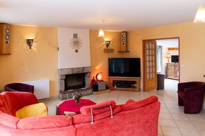 Un salon avec une cheminée, un téléviseur et un canapé rouge.