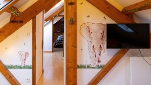 Una habitación con vigas de madera, un televisor y cuadros de elefantes.