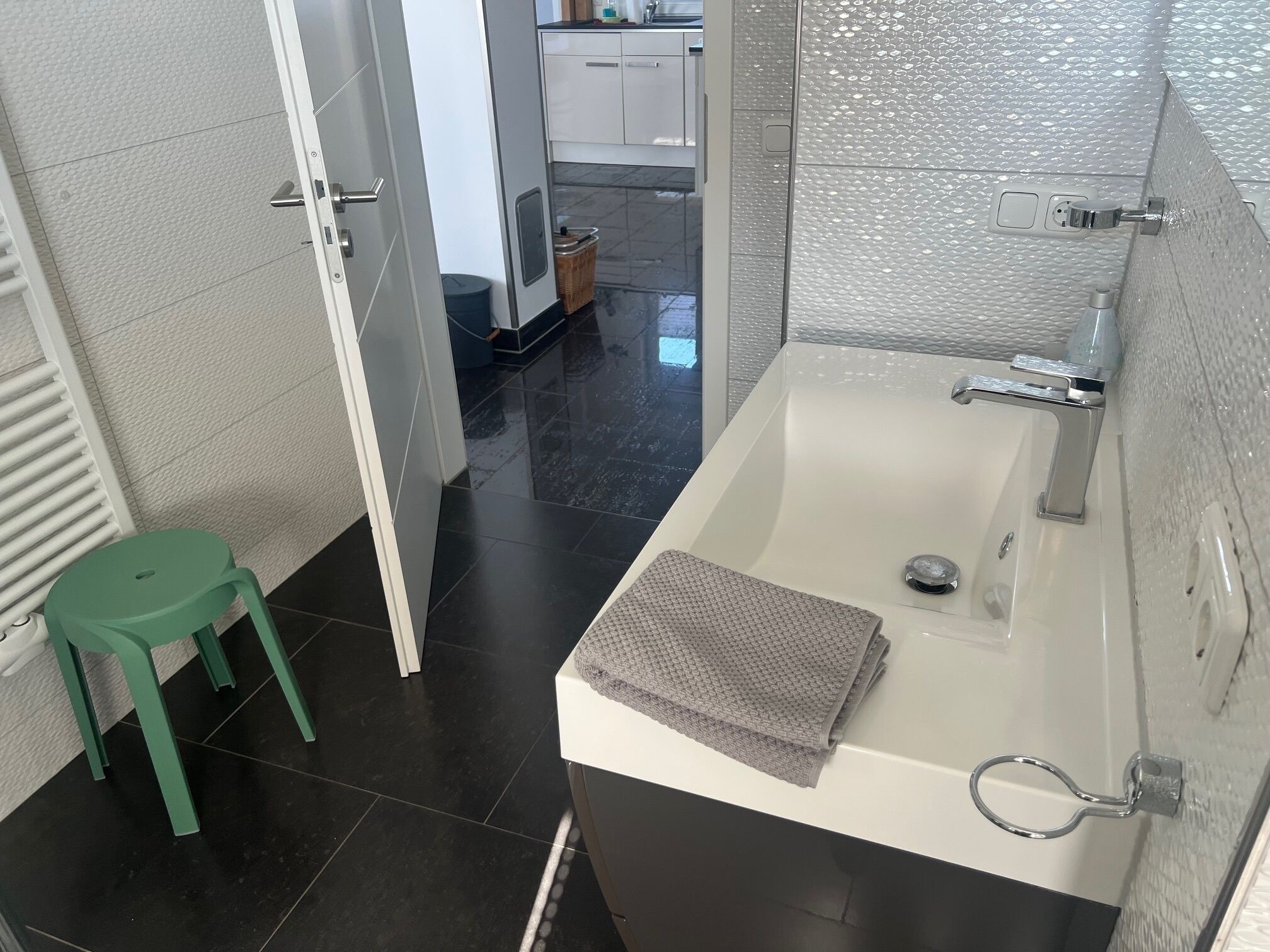 Un baño con una bañera, un taburete verde y una toalla sobre el borde.