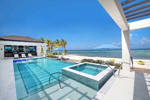 Un espace piscine avec vue sur l’océan, un jacuzzi et des chaises longues.
