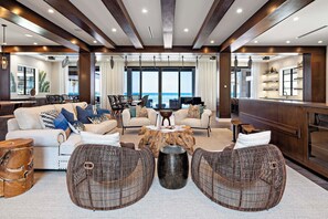 A spacious living area with a view of the sea, furnished with sofas, chairs, and a coffee table.