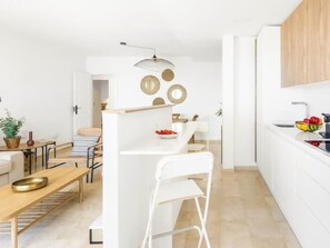 Uma cozinha moderna com armários brancos, bancada branca e luminária pendente.