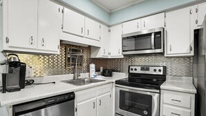 A kitchen with white cabinets, stainless steel appliances, a microwave, toaster, and dishwasher. - A Place At The Beach #3C Short Walk to the Beach! (North Myrtle Beach)