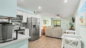A modern kitchen with a refrigerator, microwave, and stove. There is a dining area with a table and chairs. - A Place At The Beach #3C Short Walk to the Beach! (North Myrtle Beach)