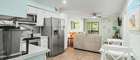 A modern kitchen with a refrigerator, microwave, and stove. There is a dining area with a table and chairs.