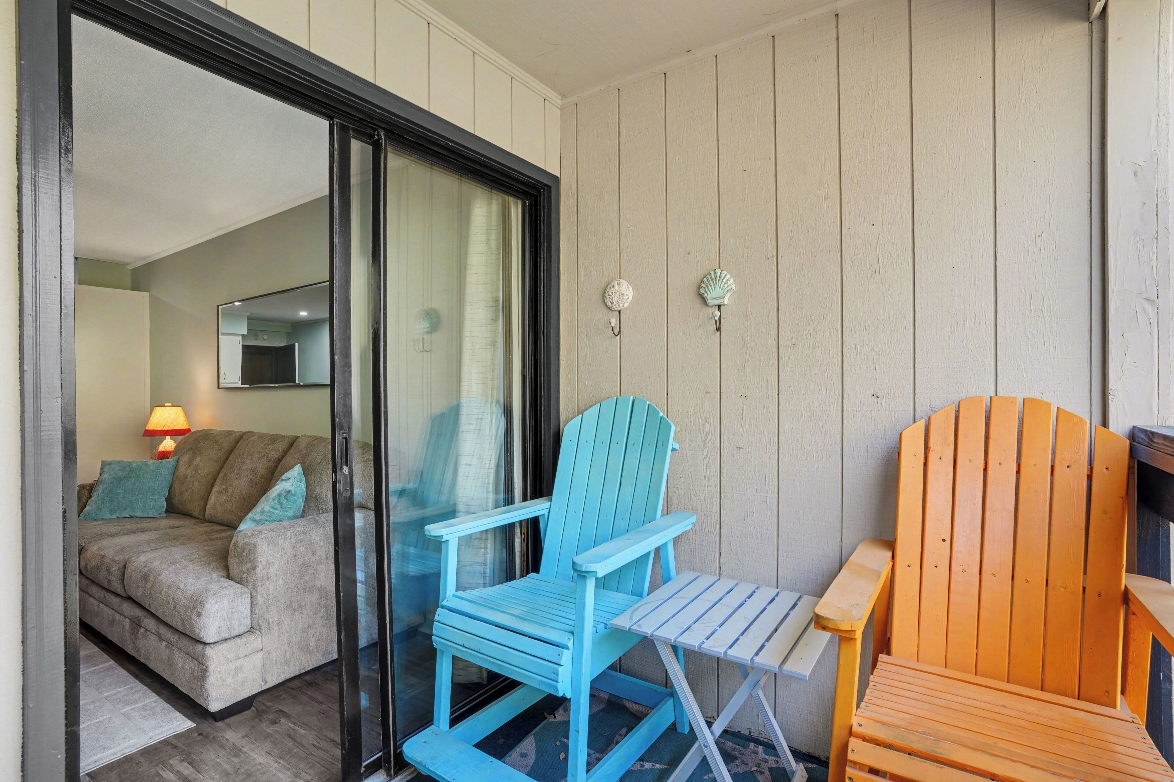 Quarto com porta de vidro deslizante que dá para uma sala de estar, uma cadeira Adirondack azul e uma cadeira de madeira.