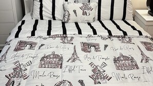 A bed with a white and black striped bedspread featuring Paris landmarks. - Nice family home (Hiram)