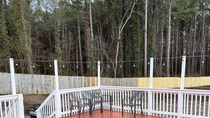 A wooden deck with a white railing, surrounded by a wooden fence and trees. - Nice family home (Hiram)