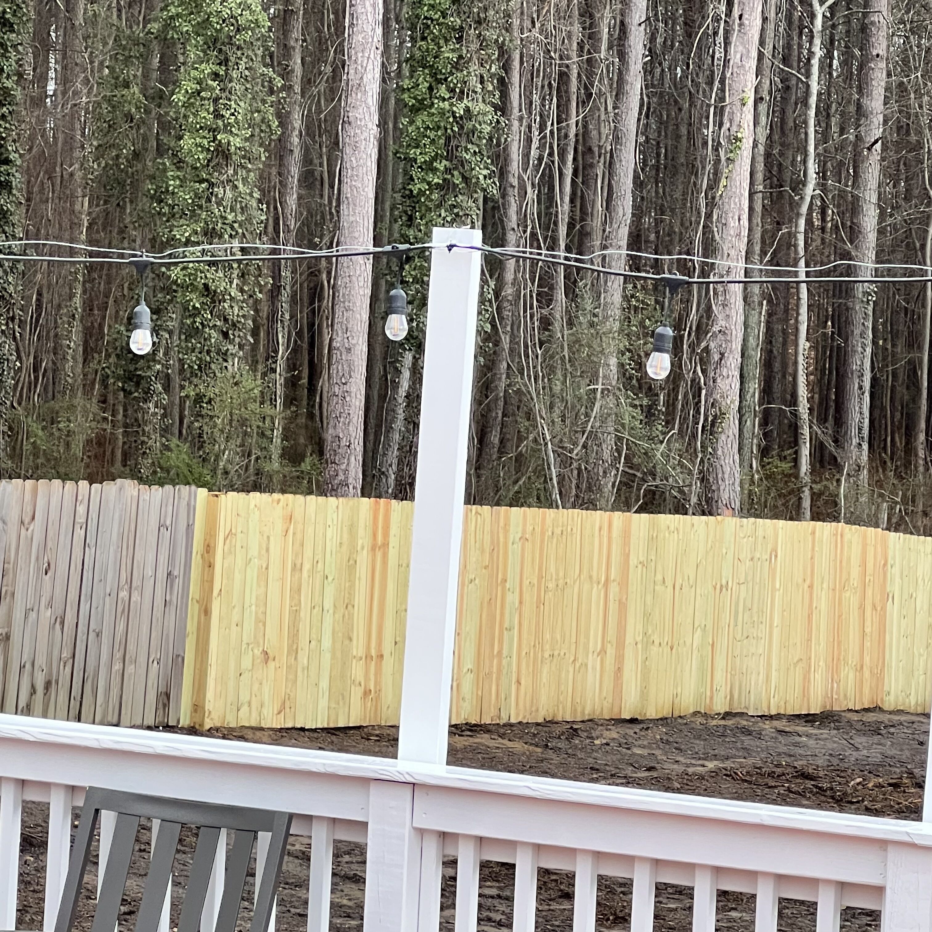 A wooden fence with a white railing, surrounded by trees.
