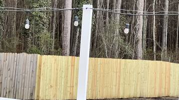 A wooden fence with a white railing, surrounded by trees.