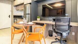 Una cocina moderna con armarios de madera, horno empotrado y una zona de comedor con sillas naranjas.