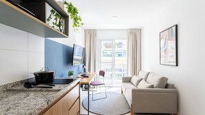 Una cocina moderna con encimera de granito, comedor con mesa y sillas, sofá y un ventanal con cortinas.