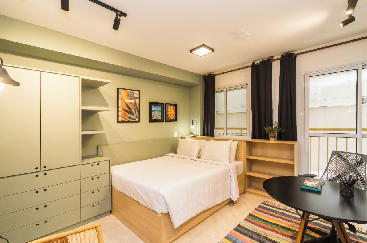 Une chambre à coucher avec un lit, une armoire, un bureau et une fenêtre avec des rideaux.