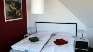 Ein Schlafzimmer mit einem Bett, zwei Nachttischen, einer Pendelleuchte und einem Bild an der Wand.