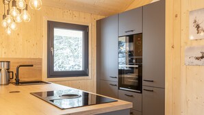 Una cocina moderna con una isla integrada, electrodomésticos de acero inoxidable y un ventanal con vistas a árboles nevados.