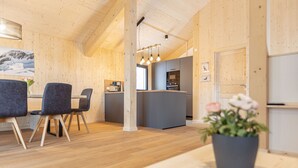 Un interior moderno con paredes de madera, una zona de cocina y un comedor con sillas y una mesa.