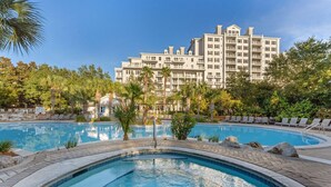 Un hôtel doté d’une grande piscine entourée de chaises longues et de palmiers.
