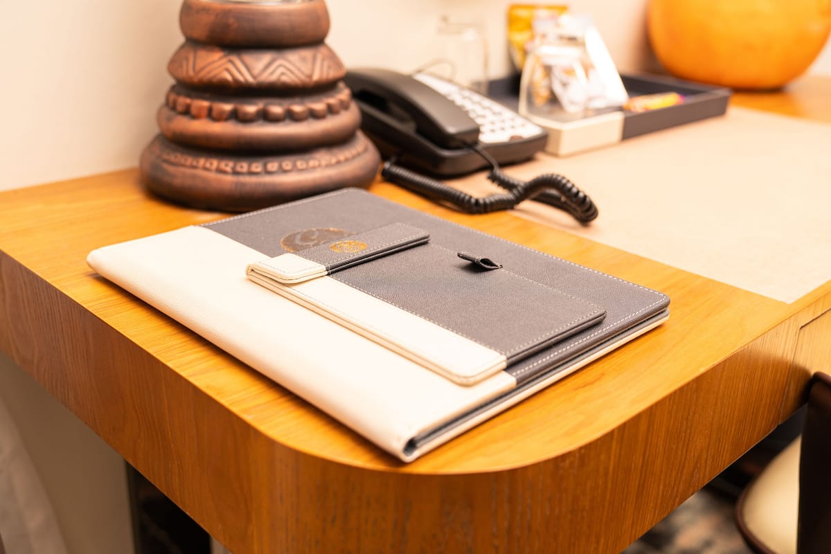 Een houten bureau met een notitieboek, pen en telefoon.